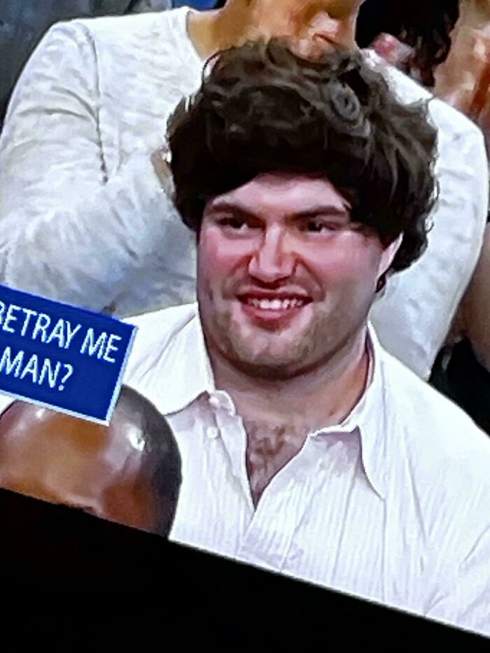 A man with a very frizzy, unkempt bad hair day, smiling broadly while looking at the camera, going viral.