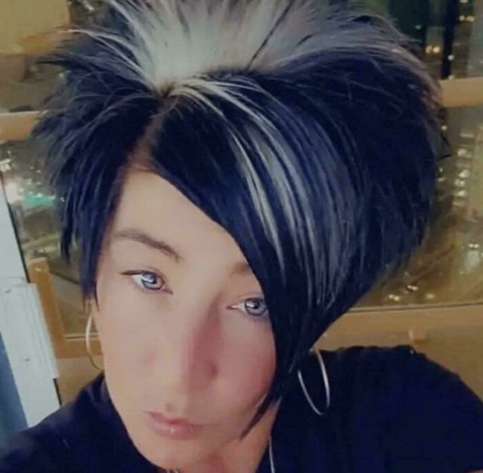 A woman with a bad hair day, showcasing a dramatic black and white spiky hairstyle and blue eyes.