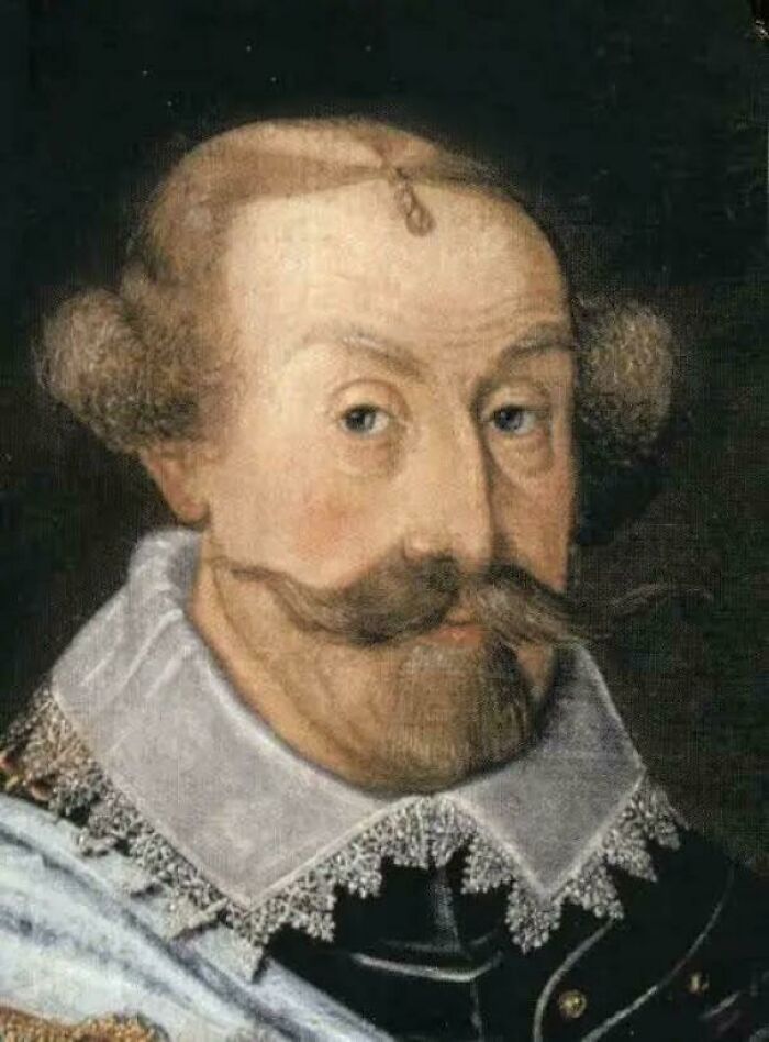 An old painting of a man with an elaborate bad hair day, featuring side buns and a mustache, is shown.