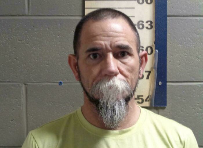 Mugshot of a man with a goatee and short hair, showcasing a bad hair day.