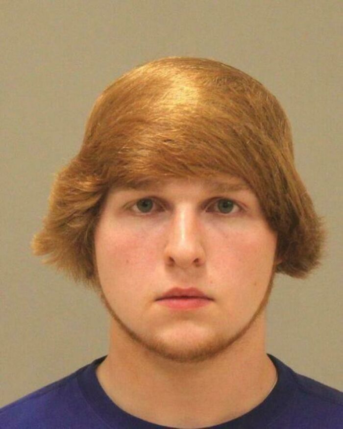 A young man with a peculiar bad hair day hairstyle, light brown hair with a side part.