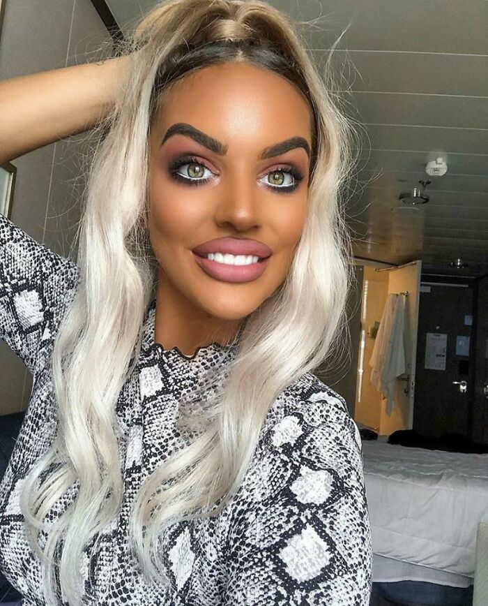 A woman with heavily bronzed skin and exaggerated makeup after a beauty salon visit, looking significantly worse.