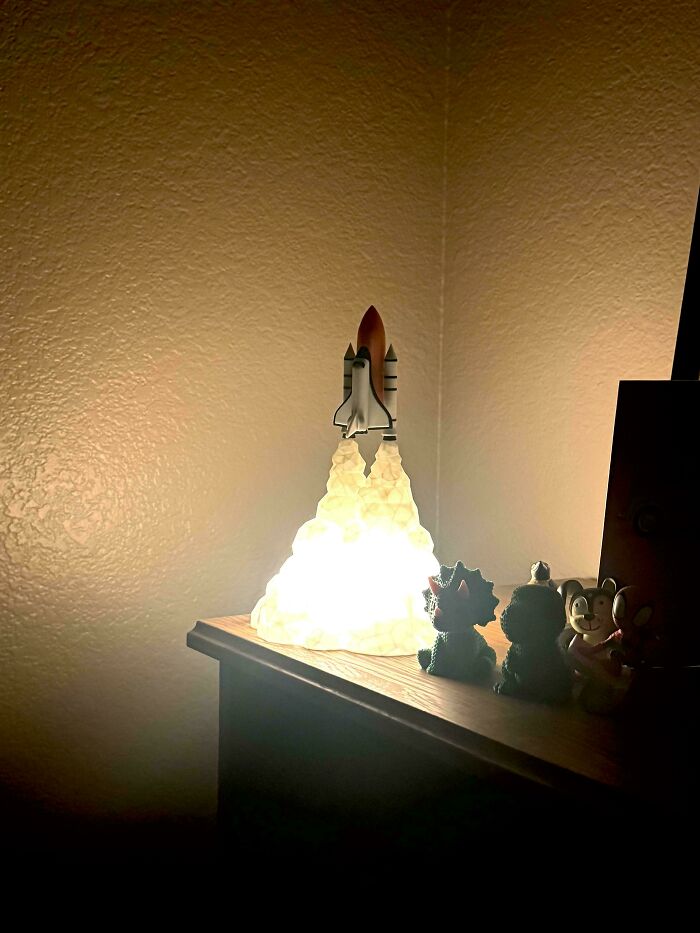 A rocket ship night light on a dresser, with small figurines, exemplifying the wholesome and fun side of being a dad.