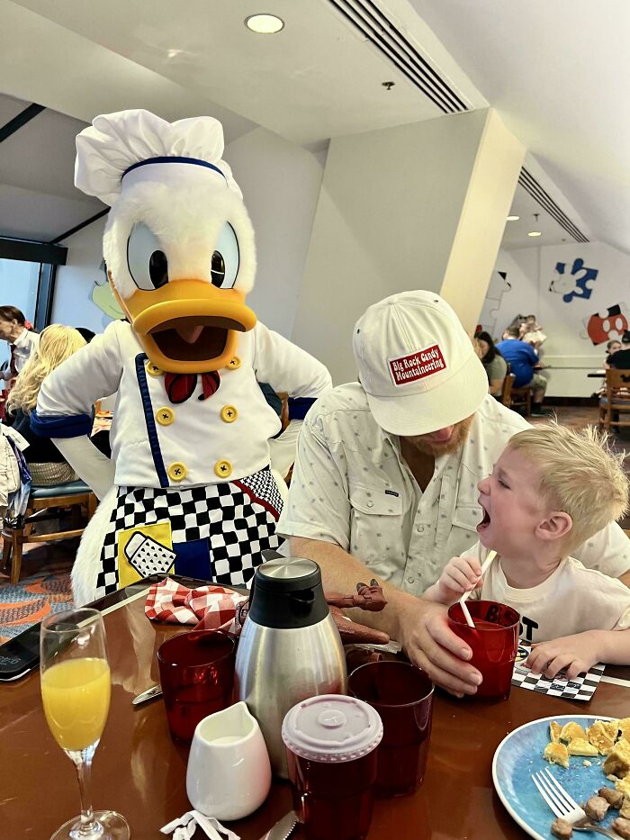 A dad and child having a fun character breakfast with Donald Duck.
