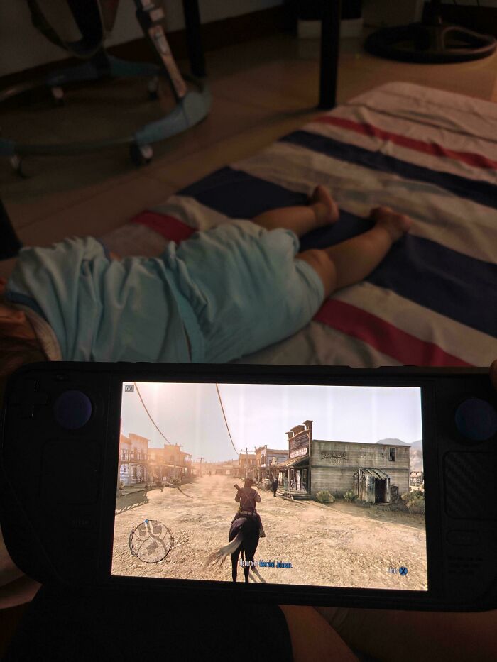 A child lying on the floor while a dad plays a video game, capturing the fun side of being a dad.