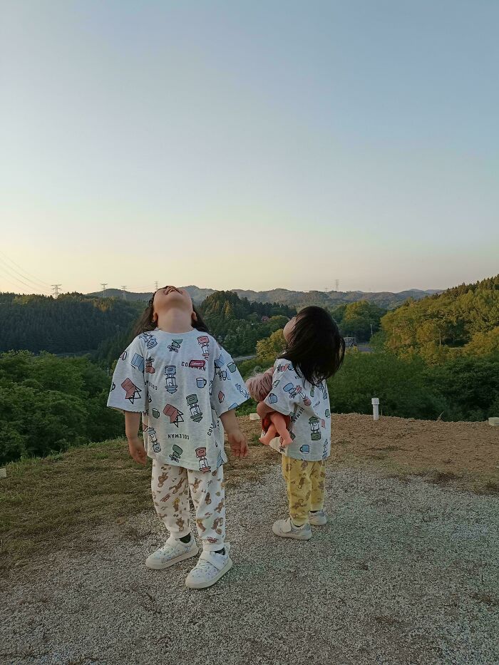 Two young children looking up at the sky in a scenic outdoor setting, reflecting the fun side of being a dad.