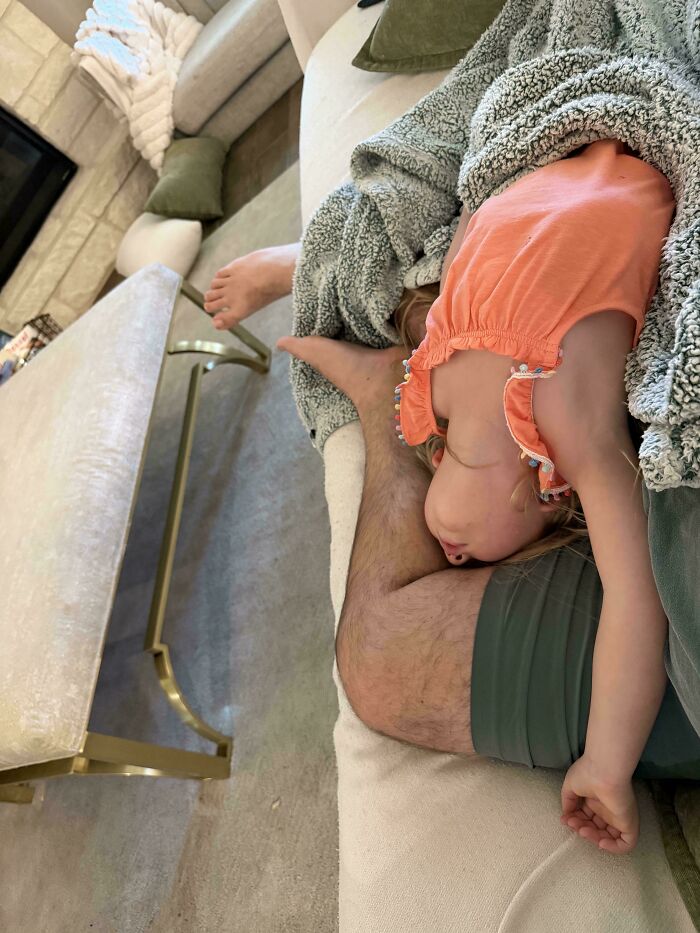 A dad relaxing on a couch with his child upside down on him, showcasing the wholesome and fun side of being a dad.