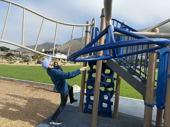 A dad goofing around on a playground, showing the wholesome and fun side of being a dad.