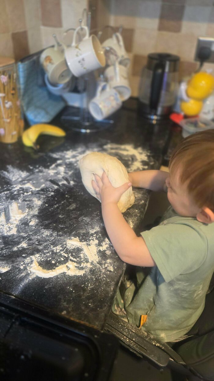 Toddler playing with dough and flour on a kitchen counter, a fun side of being a dad.