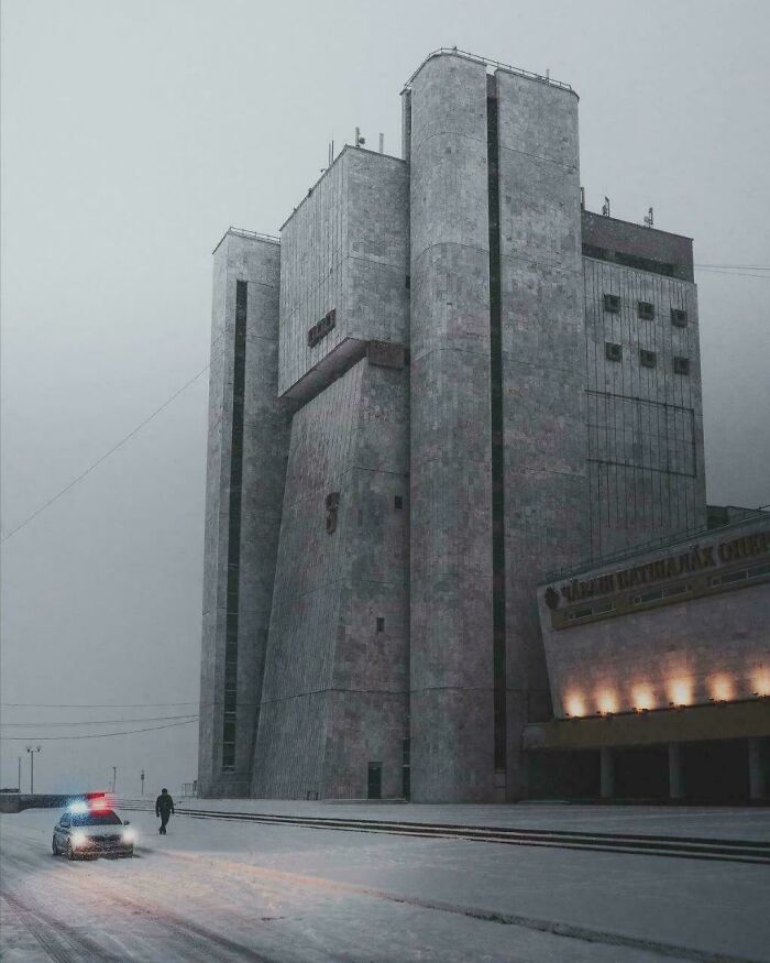 A brutalist building in a snowy landscape with a police car, an interesting photo.