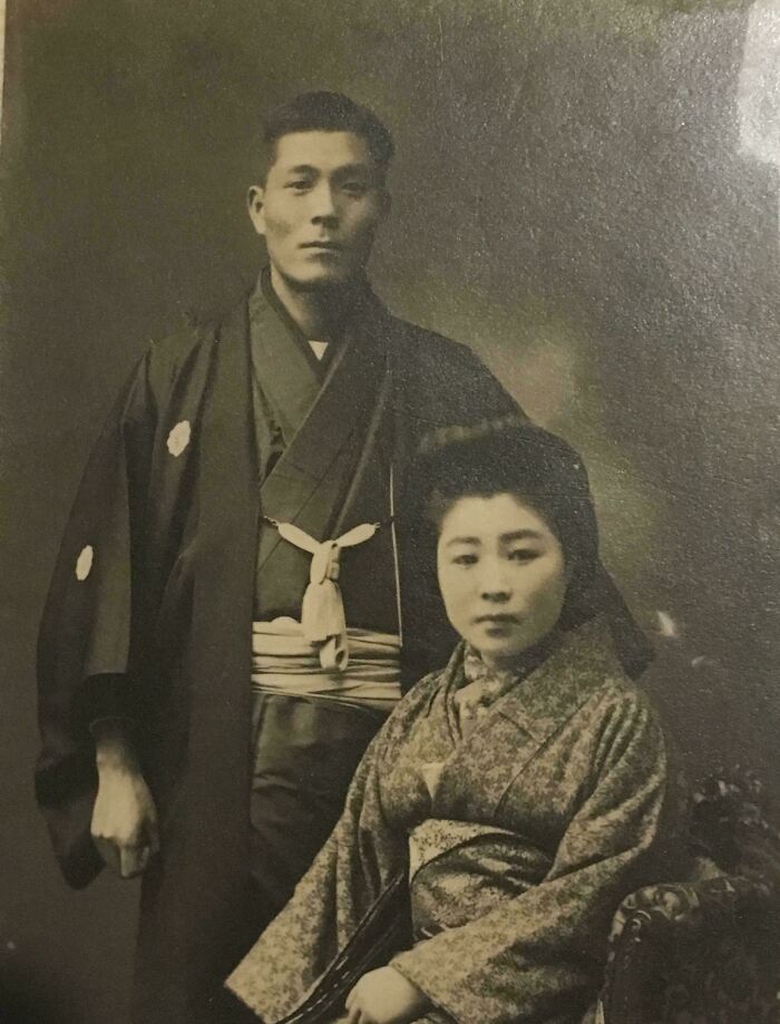 An interesting old black and white photo of a Japanese couple in traditional kimonos, looking directly at the camera.