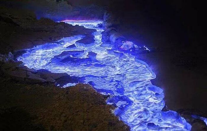 An interesting vibrant blue lava river flowing in a dark environment, illuminating its surroundings with an otherworldly glow.