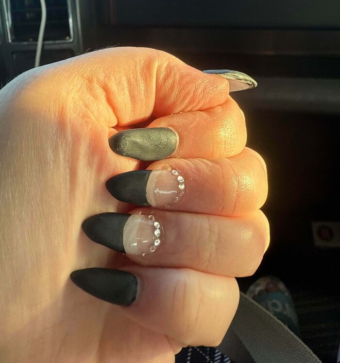 A hand with poorly done black and clear tip acrylic nails, featuring rhinestones, looking significantly worse than expected.