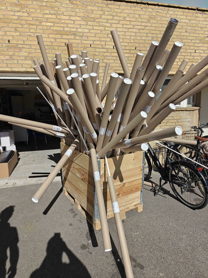 A Funny 'You Had One Job' Fail: Numerous long cardboard tubes are haphazardly piled in a wooden crate, displaying a funny fail.