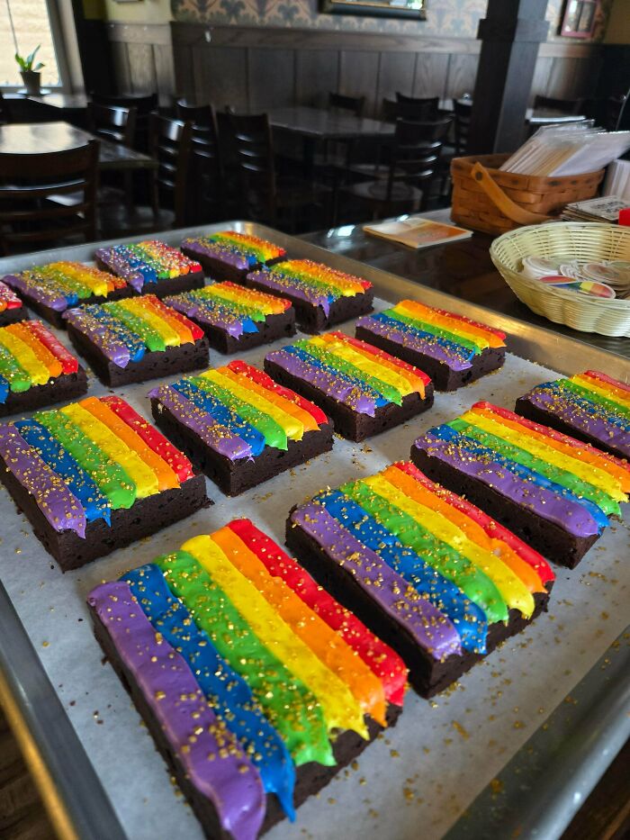 Delicious treats from a skilled baker: a tray of brownies with colorful rainbow frosting, sprinkled with gold dust.