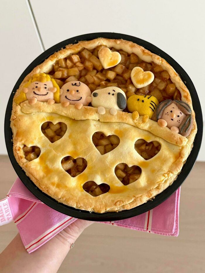A creative apple pie featuring Snoopy and friends characters, showcasing a baker's amazing and delicious treats.