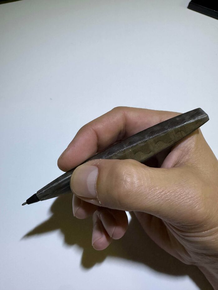 A hand holding a textured, handmade pen, highlighting the craftsmanship and talent in creating this unique project.