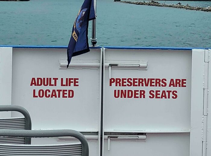 Adult life and preservers under seats sign on boat with water background