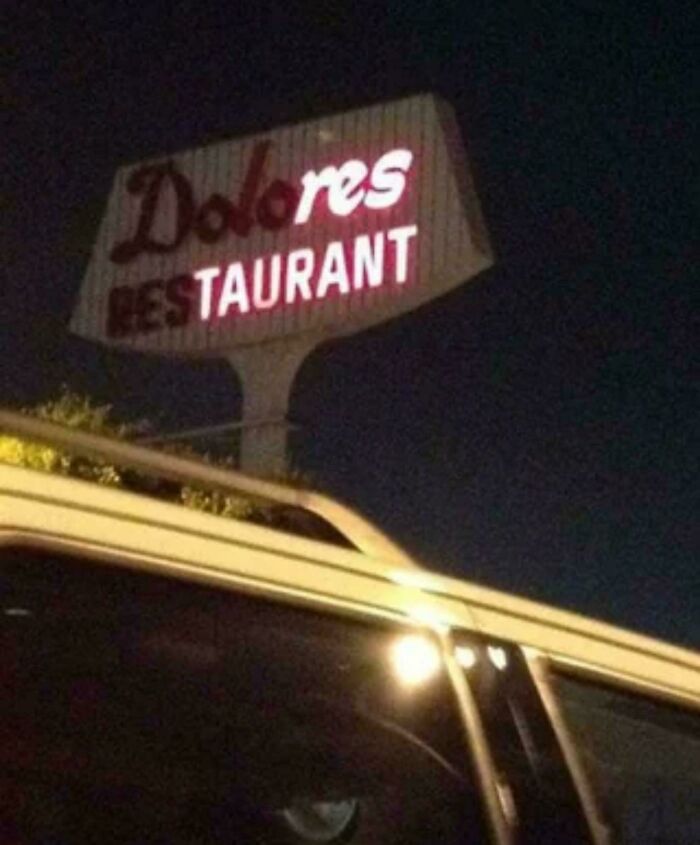Damaged restaurant sign with missing letters at night