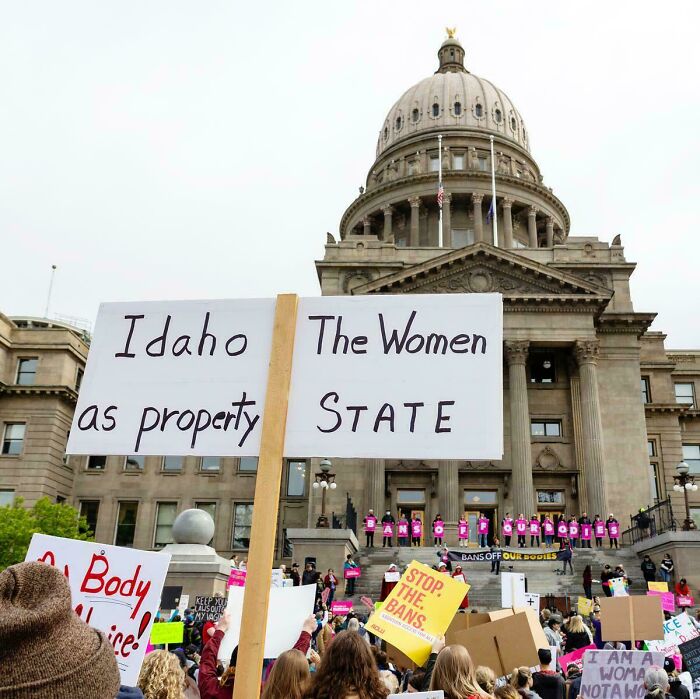 Protest sign at Idaho capitol about women as property with crowd