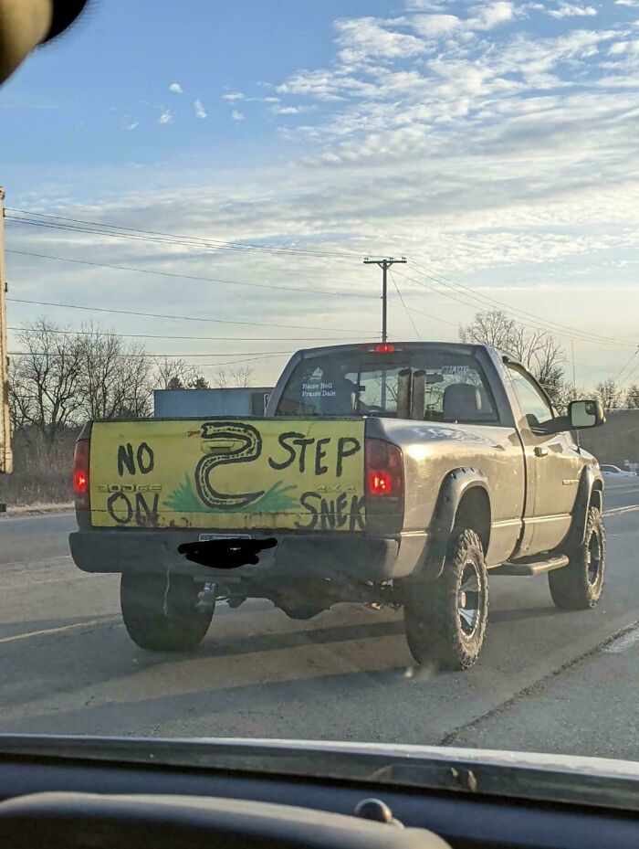 Pickup truck with handmade warning sign saying no step on snake