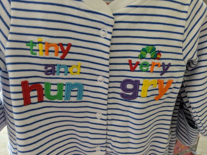Baby outfit with misspelled words tiny and hun very gry on striped fabric