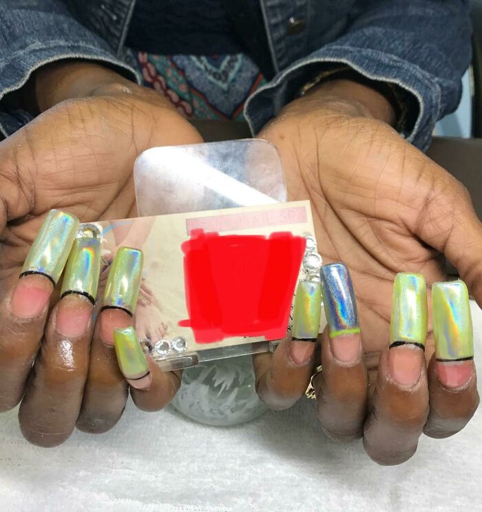 Hands with unusually long, mismatched, square-shaped false nails with a holographic finish, demonstrating a beauty salon blunder.