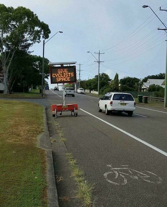 Irony sign saying give cyclists space blocking bike lane on a street
