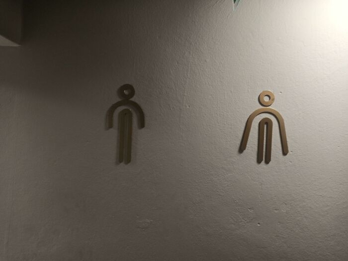 Awful design fail showing confusing restroom signs with unclear human figure shapes on wall