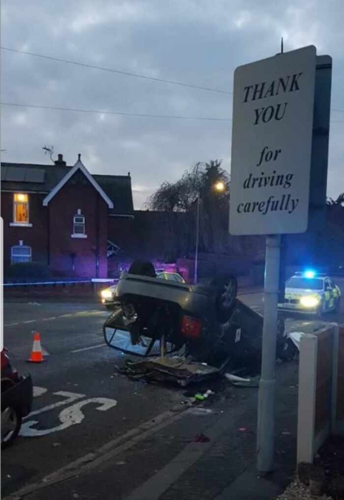 Crashed car flipped over near thank you for driving carefully road sign
