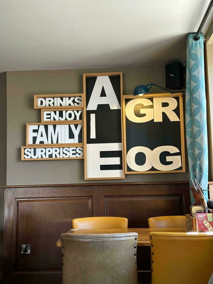 Wall art with misaligned letters ruining family drinks enjoy surprises message
