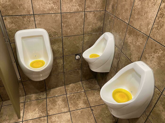 Three urinals in a bathroom corner with uncomfortable awkward placement