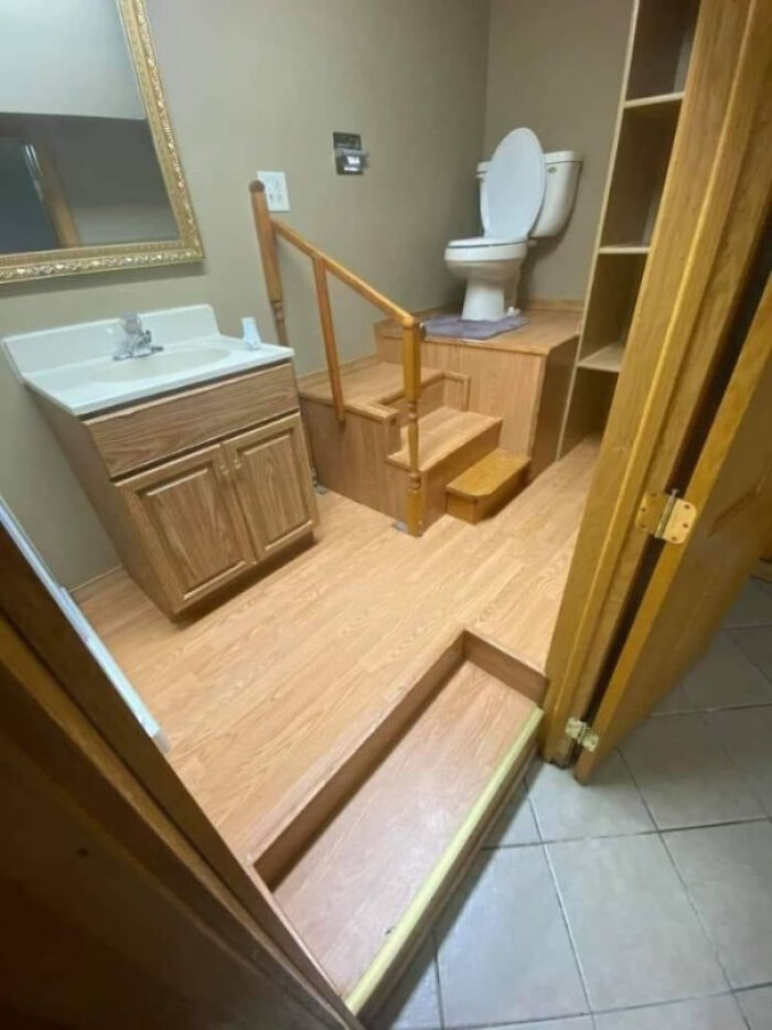 Bathroom with toilet elevated on wooden platform accessed by stairs design fail