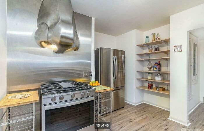 Kitchen with odd stainless steel stove hood and limited counter space design fail