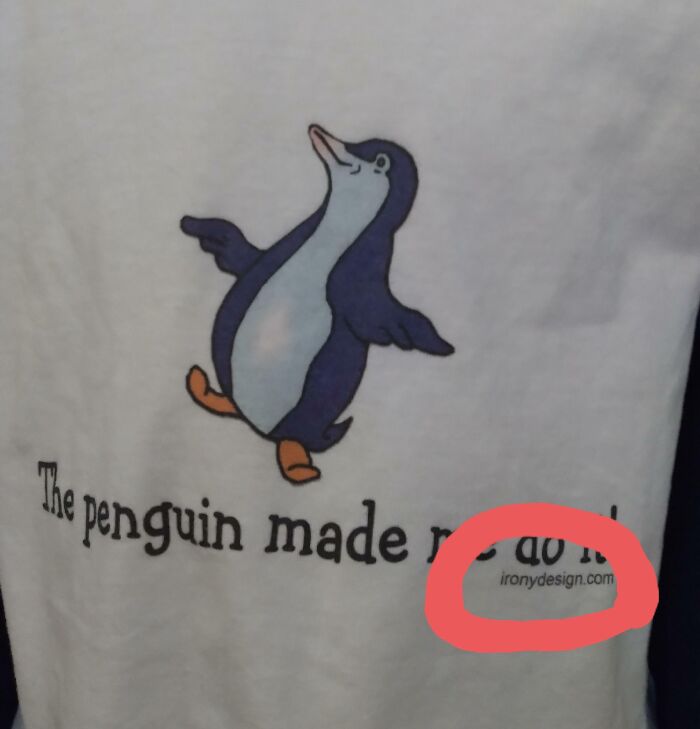 A white t-shirt with a penguin illustration and bad clothing designs text that says 'The penguin made r' with 'ironydesign.com' circled.