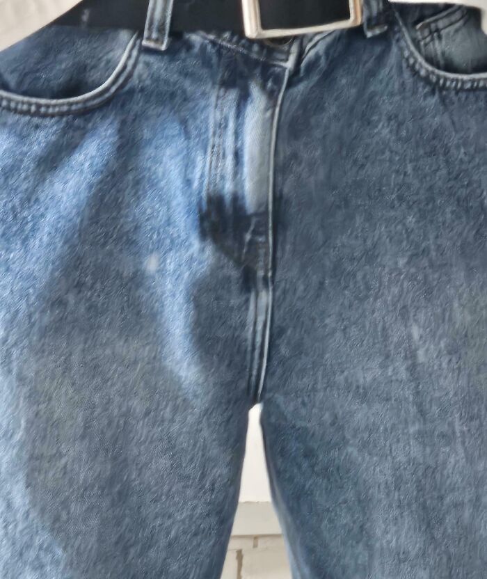 Close-up of blue jeans with an off-center zipper, exemplifying a bad clothing design.