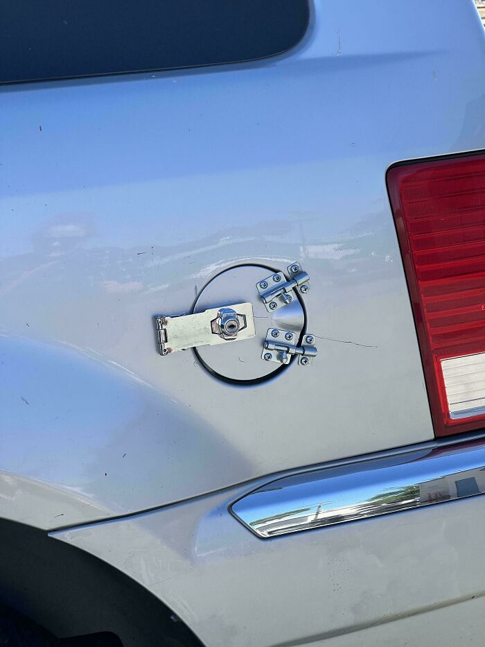 A car's fuel cap secured with multiple latches and a padlock, an inventive clever solution.