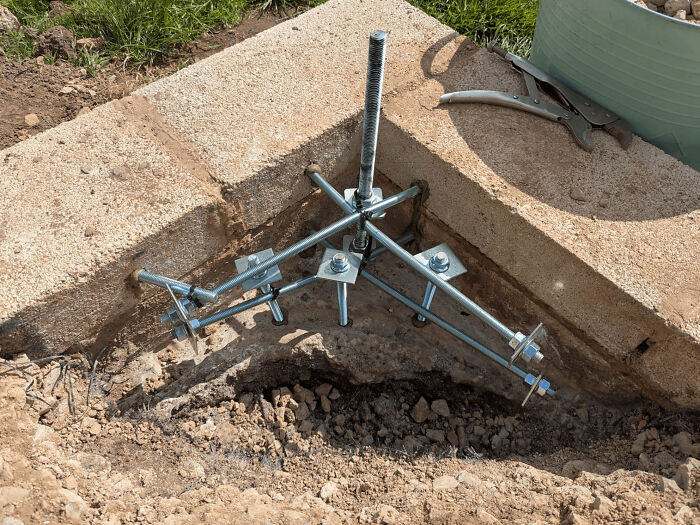 Metal rods and bolts form a complex anchor system in a concrete base, showcasing clever solutions.