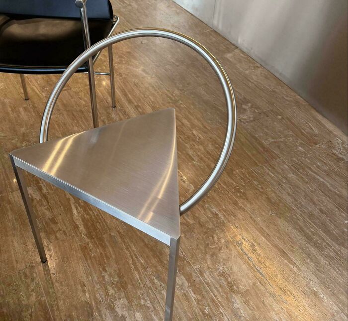 A baffling image of a unique, modern metal table with a triangular top and a circular back, prompting questions about its design.
