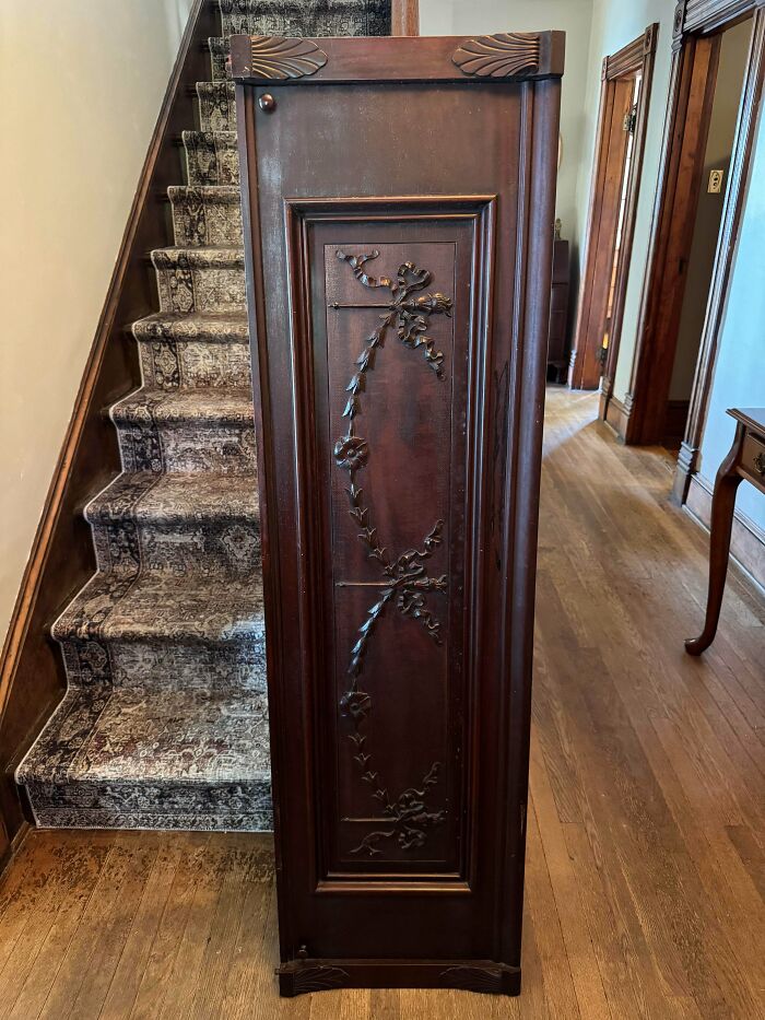 Tall dark wooden cabinet with carved floral detailing, an old treasure discovered by antique lovers