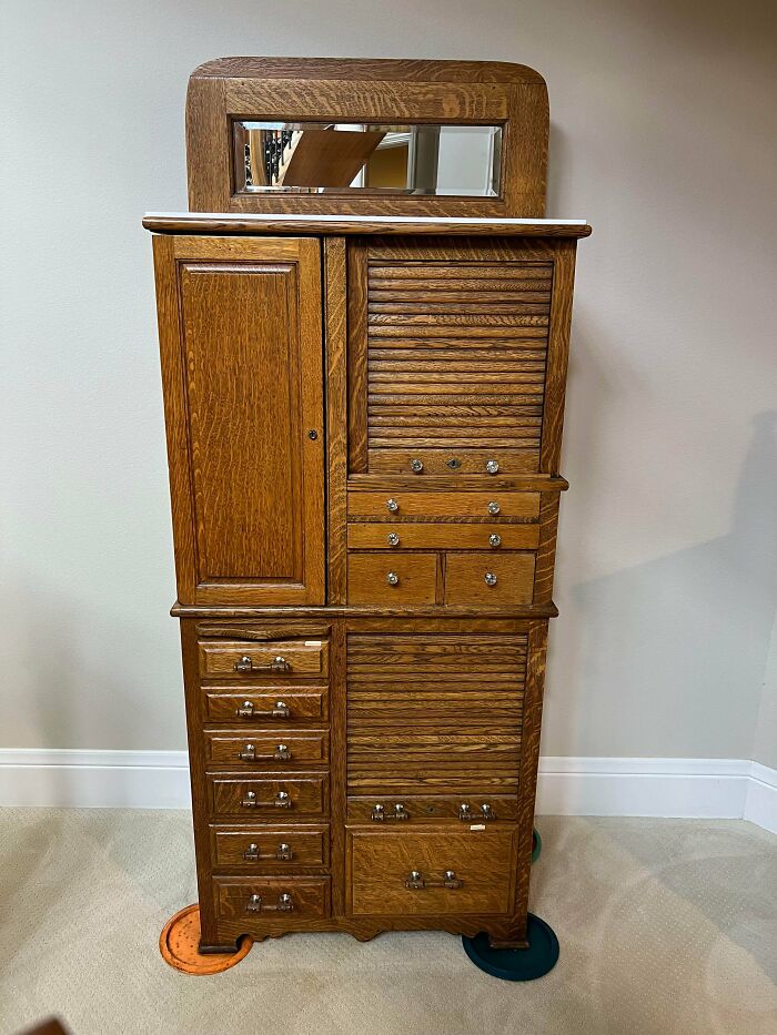 Intricate wooden dental cabinet featuring drawers and mirror, unique among old treasures.