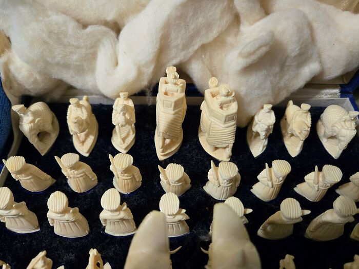 A set of intricately carved ivory chess pieces displayed in a box, highlighting old treasures for antique lovers.