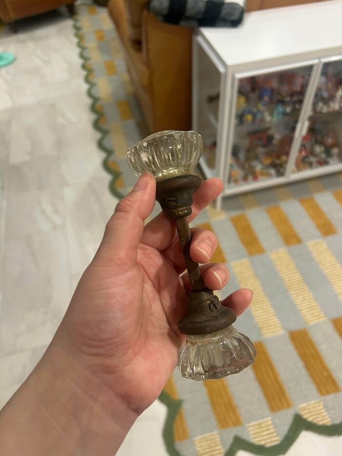 Person holding a vintage glass doorknob assembly, part of a collection of old treasures