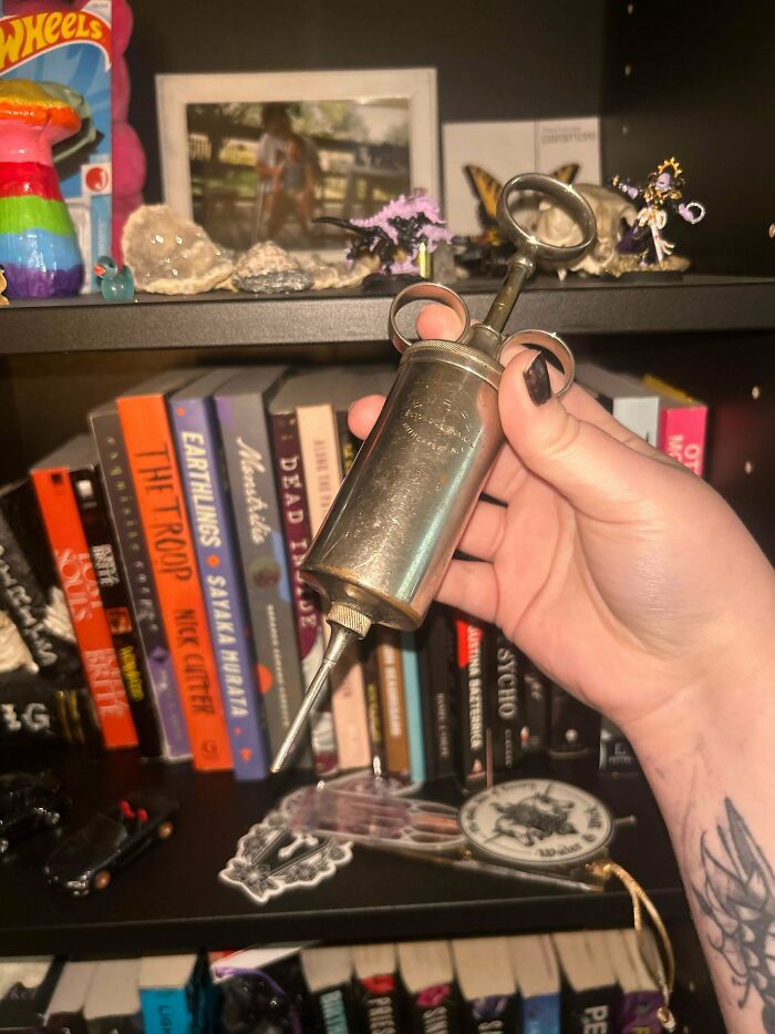 Hand holding an old metal syringe, one of many old treasures discovered by antique lovers