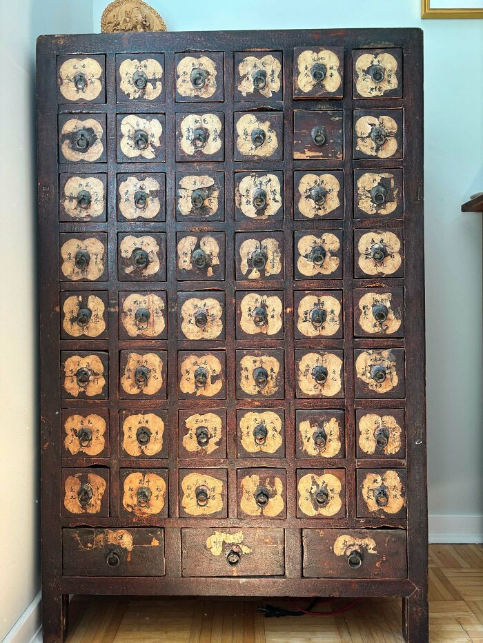 A tall vintage apothecary cabinet with many small drawers, perfect for antique lovers.