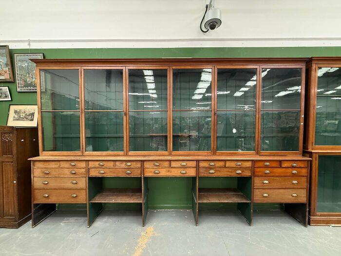A massive antique wooden display cabinet with glass doors and multiple drawers
