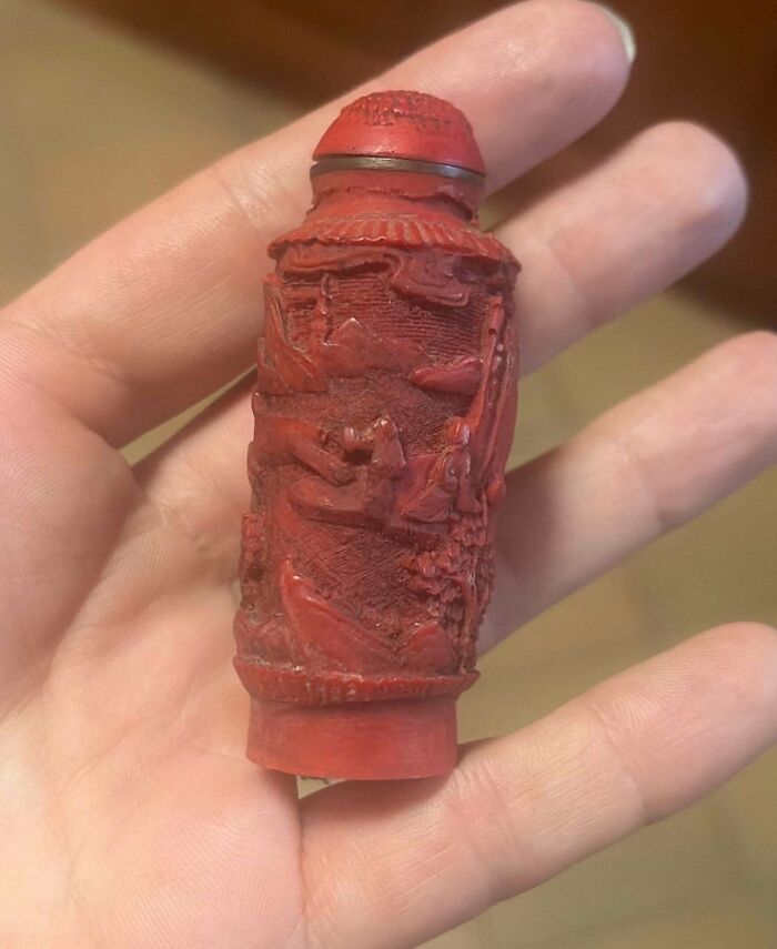 Hand holding a tiny antique red carved Chinese cinnabar lacquer snuff bottle