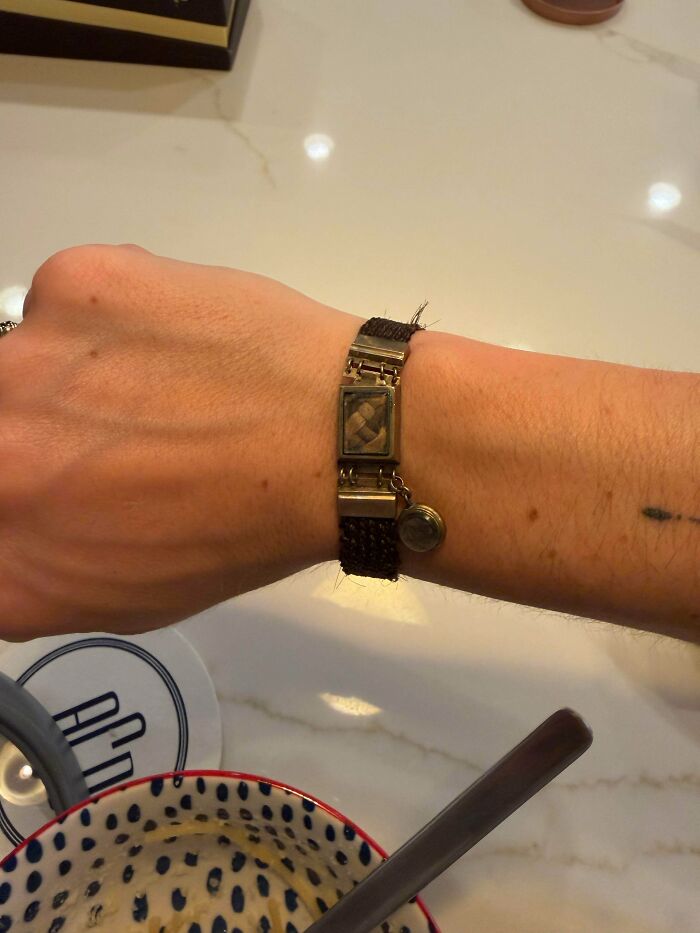 Hand wearing a woven hair memorial bracelet, an example of old treasures and unique finds for antique lovers.