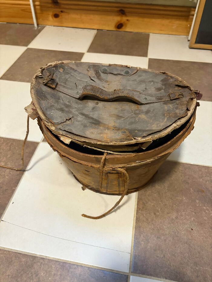 A weathered round wooden box with a worn leather top, showcasing unique old treasures.