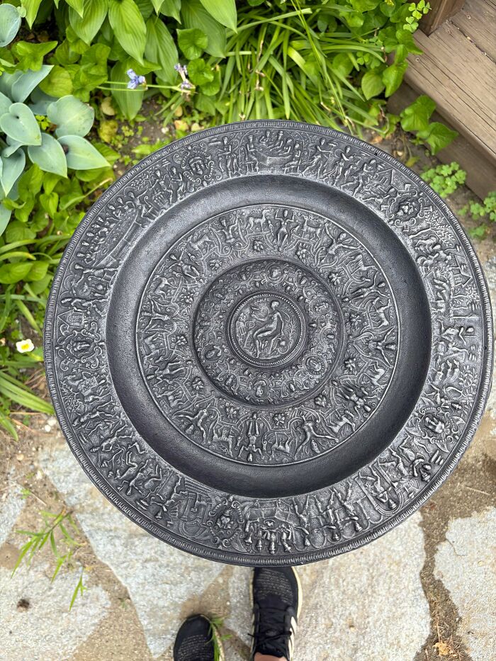 Top-down view of an intricately carved metallic plate, a fascinating find for antique lovers seeking old treasures.